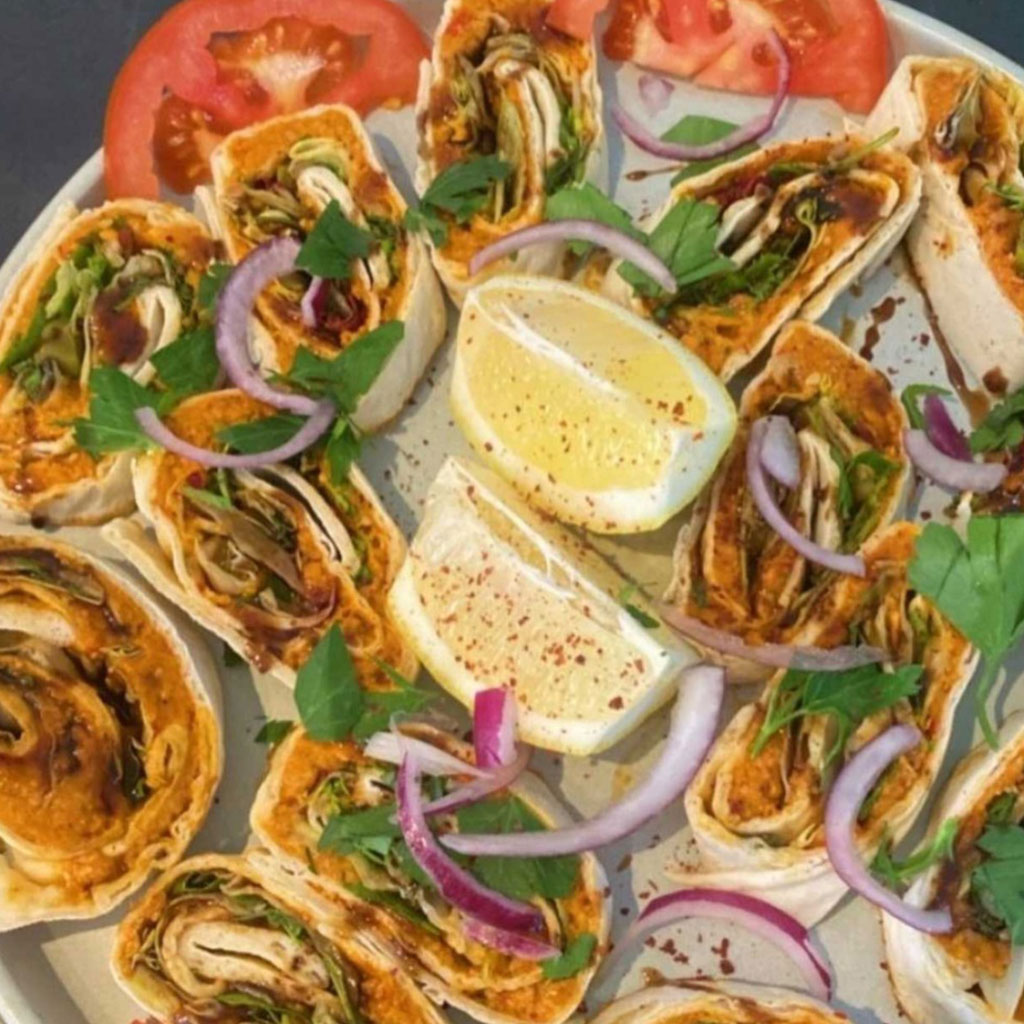 Teller mit Wrap Röllchen mit Hähnchen und Soße dazu Zitrone und Zwiebeln