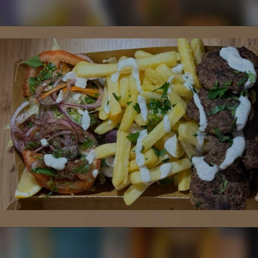 Pommes mit weißen Soßenstreifen neben Fladen und Fleischbällchen, herzhaft